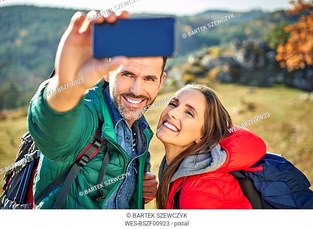 Happy couple on a hiking trip in the mountains taking a selfie