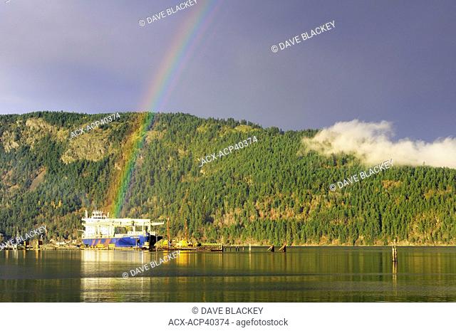 The freighter, Star Harmonia, loading lumber while under a rainbow at the dock in Cowichan Bay, British Columbia, Canada
