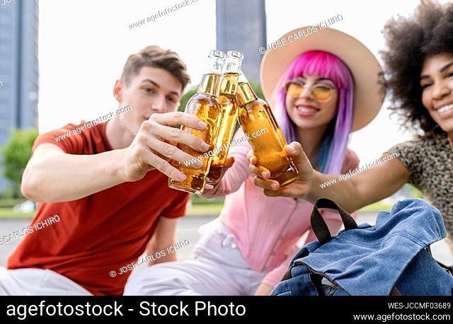 Multi-ethnic male and female friends toasting drinks at park