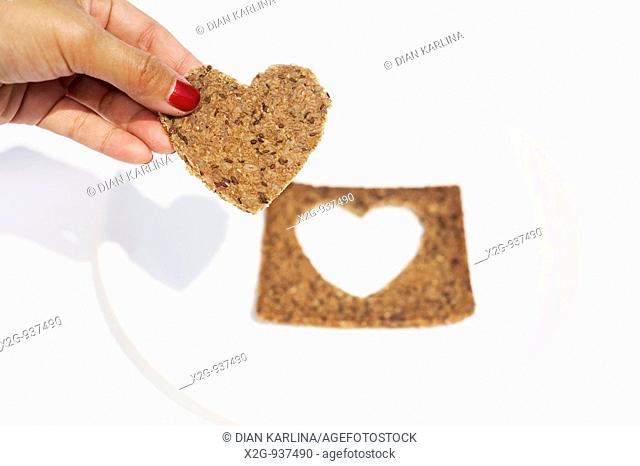 A woman's hand holding a heart-shaped rye bread