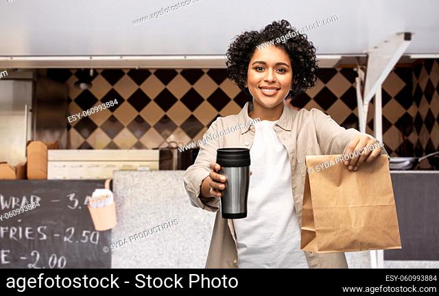 happy woman with thermo cup and food in paper bag