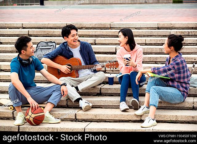 The young college students sat on the steps to play guitar to sing