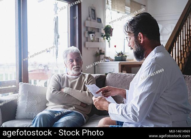 Male professional doctor consulting senior patient during medical care visit. Young man physician and old mature senior talking providing medical assistance...
