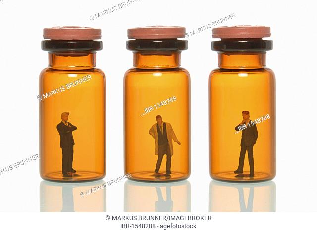 Two miniature business man figures and a doctor figure in glass pill bottles, symbolic image for doctors against the pharmacy business