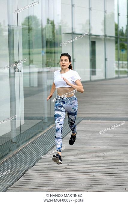 Young woman running along building in the city