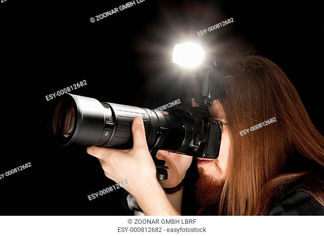 Photographer using DSLR camera with flash and telephoto lens