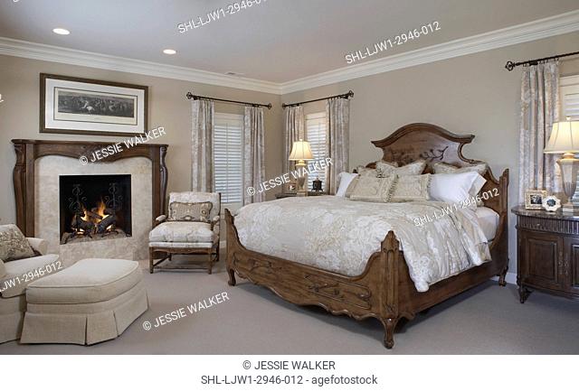 MASTER BEDROOM: Monochromatic cream and white , traditional, gas fire, seating area to left of bed, corner windows have shutters and ring top curtains