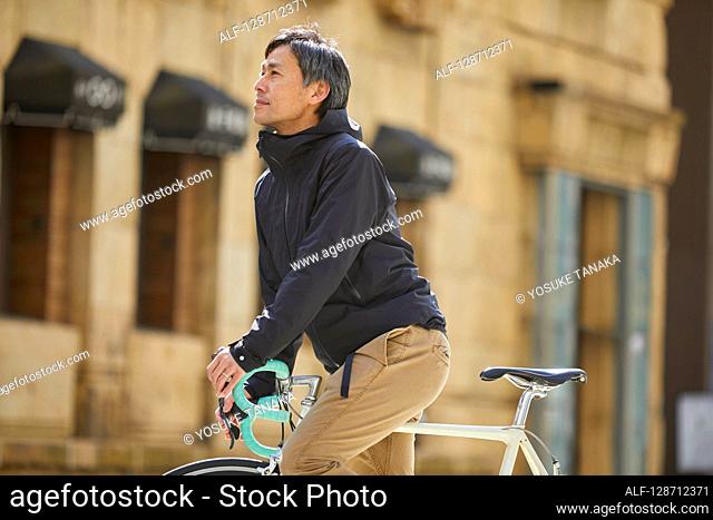 Middle Aged Japanese Businessman Riding A Bicycle