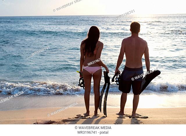 Couple standing with snorkeling equipments on the beach