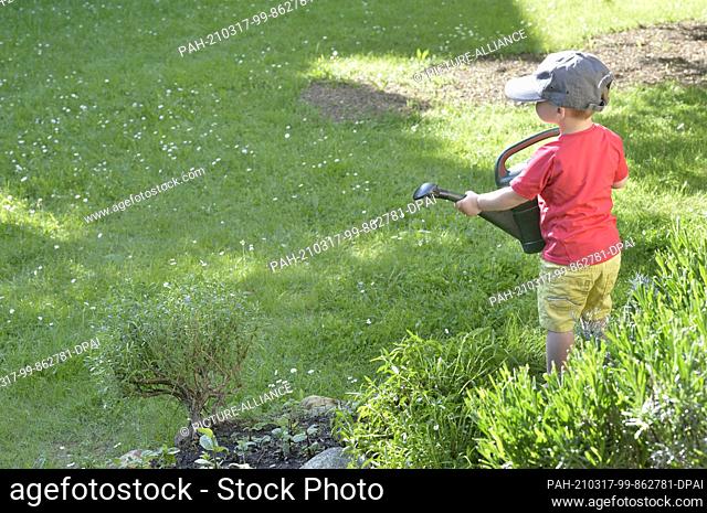 09 May 2018, Saxony, Leipzig: Watering flowers, fruit and vegetables. A little boy helps out in grandma and grandpa's garden