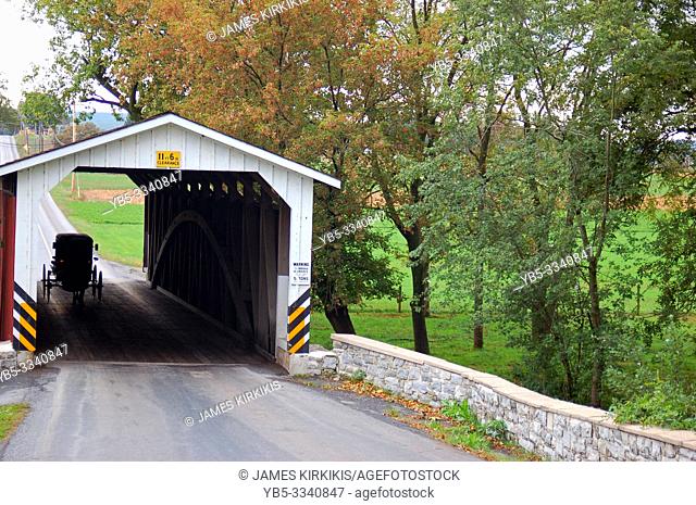An Amish horse and buggy traverse through a covered bridge in Lancaster County, Pennsylvania
