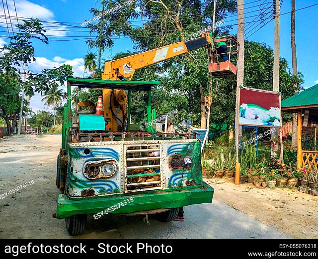 Colorful old classic cherry picker for maintenance at overhead lines on the roadway of the island of Ko Phayam in the south of Thailand