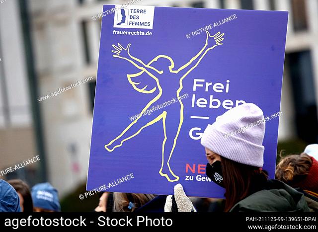 25 November 2021, Berlin: A woman carries a sign during an action of Terre des Femmes under the motto ""Live free without violence"" on the day against violence...