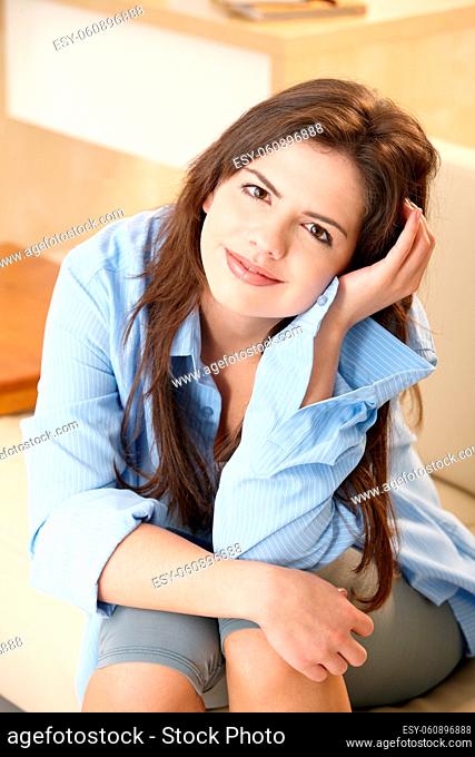 Attractive young woman smiling at camera, sitting in bright living room