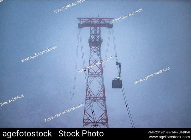 01 December 2023, Bavaria, Garmisch-Partenkirchen: The Zugspitze cable car runs up to the summit in the early hours of the morning