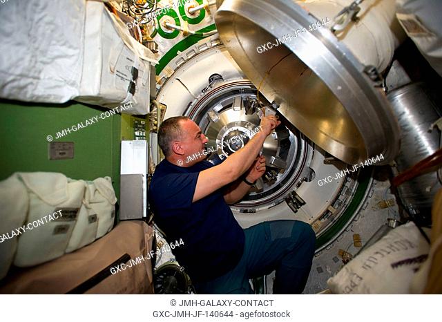 Russian cosmonaut Alexander Skvortsov, Expedition 40 flight engineer, prepares to remove the docking mechanism to gain access to the hatch of the newly attached...