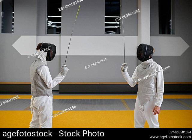 Two fencers staying with raised rapiers front of each other ready to fight. Combat sport and martial art concept