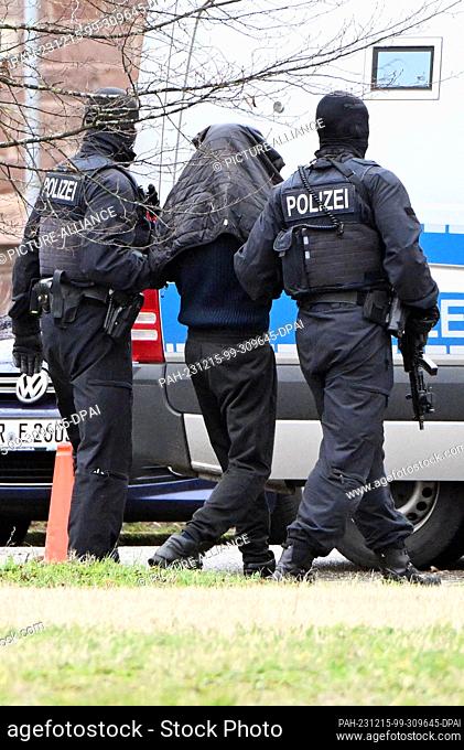 15 December 2023, Baden-Württemberg, Karlsruhe: A person is led from a helicopter to a car by police officers at a helipad