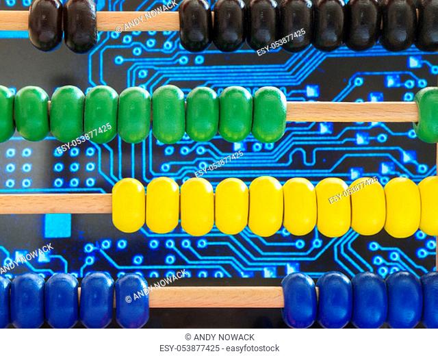Close-up of a wooden abacus with colorful beads in front of traces of an electronic circuit board