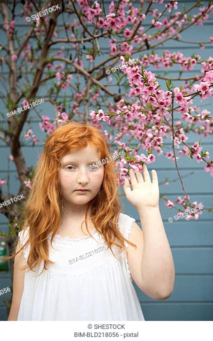Caucasian girl waving under flowering tree