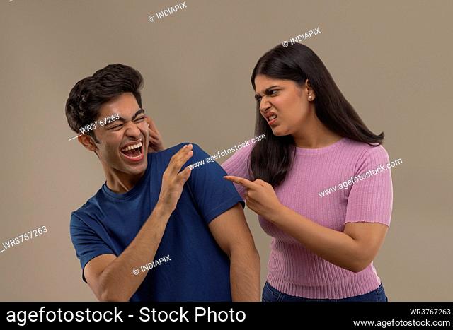 AN EXPRESSIVE WOMAN REBUKING YOUNGER BROTHER IN FUN