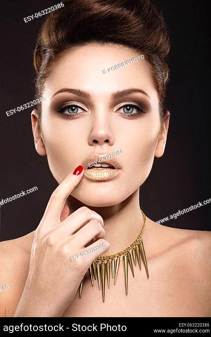 Beautiful girl with a gold accessories , creative makeup and hair. The beauty of the face. Photos shot in the studio