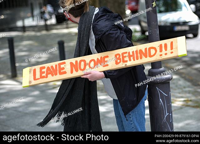 29 April 2020, Rhineland-Palatinate, Mainz: A participant in a protest action holds a sign saying ""Leave No-One Behind""