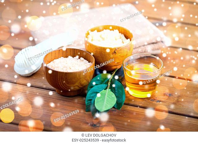 beauty, spa, bodycare, natural cosmetics and bath concept - close up of himalayan pink salt and body scrub with brush and towel on wooden table over lights and...