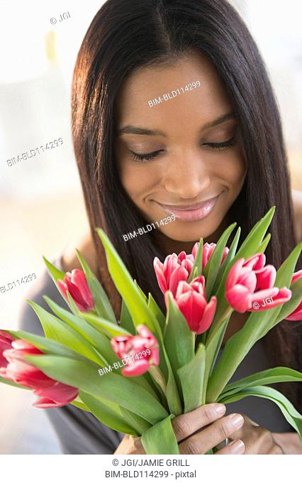 Mixed race woman smelling flowers