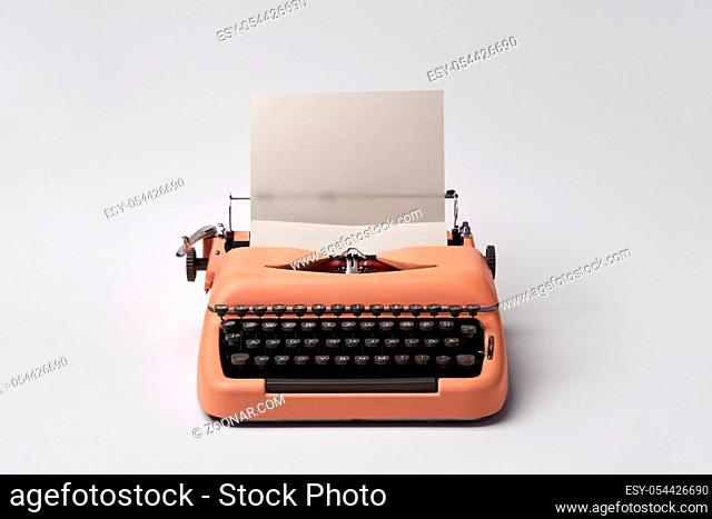 Stylish retro typewriter with a paper sheet on the light background in the studio. Horizontal