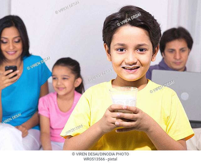 Boy holding a glass with his family in the background MR779P , MR779Q , MR779R , MR779S