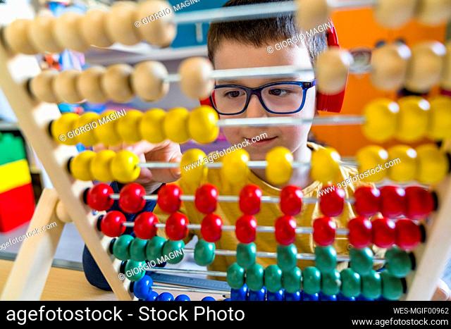 Boy calculating with colorful abacus at home