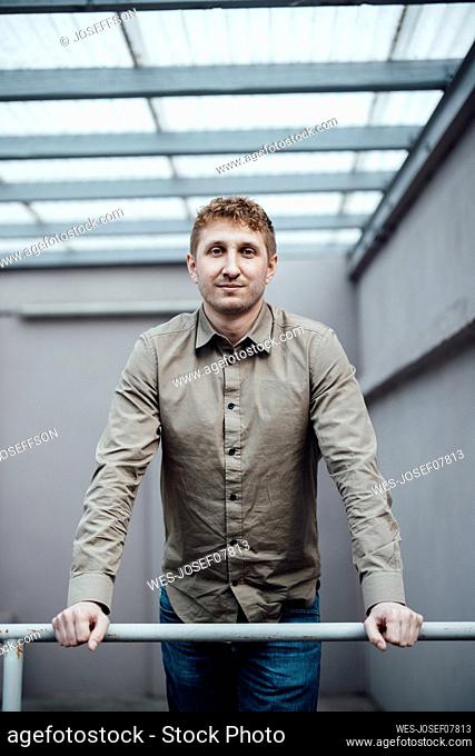 Businessman leaning on railing at work place
