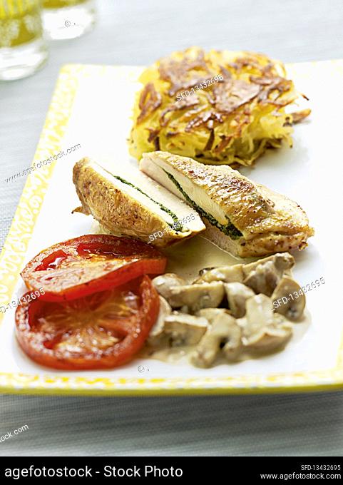 Stuffed chicken breast with grilled tomatoes, latkes and mushrooms in a cream sauce