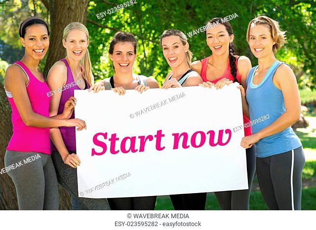 Start now against fitness group holding poster in park