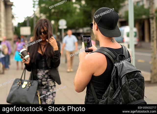 Cuple make photos on street, man photographing girl on urban space