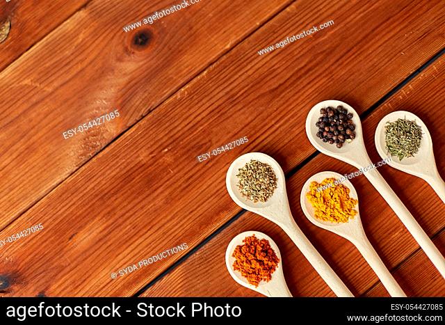 spoons with different spices on wooden table