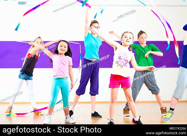 Children dancing modern group choreography with scarfs
