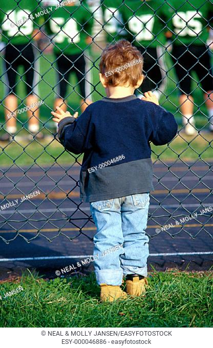 Young boy watching big kids football game