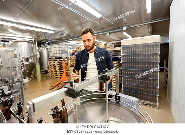 production, business and people concept - men with bottles on conveyor at craft brewery or non-alcoholic beverage plant