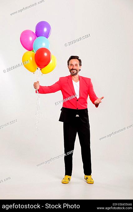 Smiling man holding pile of colorful balloons. Happy birthday concept