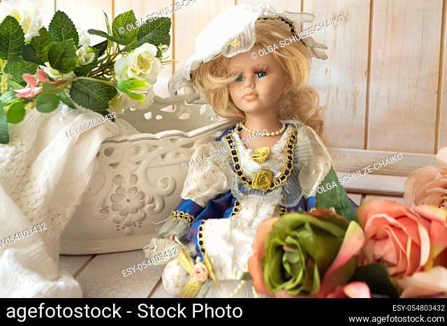 Still life in vintage style with a doll, pastel roses on a shabby background of old wooden planks