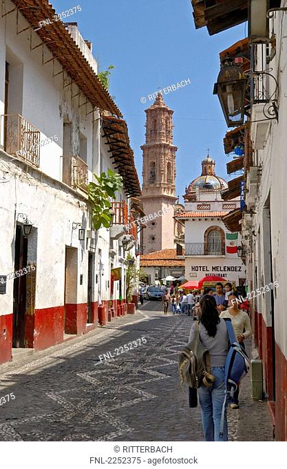 People in street with church in background, San Sebastian y Santa Prisca, Taxco de Alarcon, Guerrero, Mexico