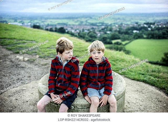 England, Somerset, Glastonbury. Two boys at the top of Glastonbury Tor at dusk