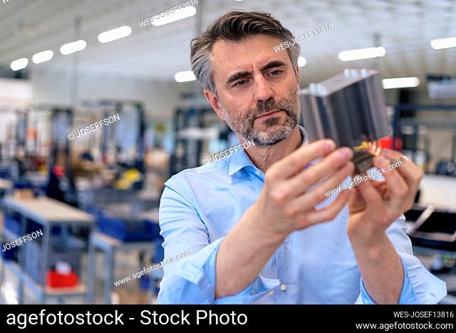 Mature businessman examining machine part in industry
