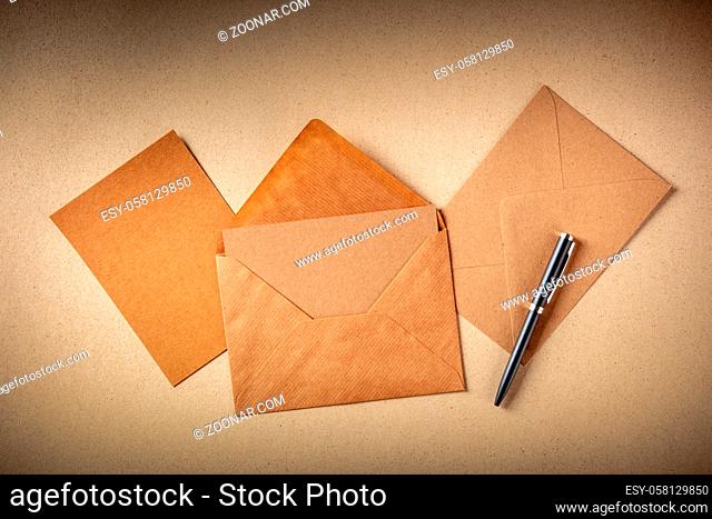 Greeting card mockup in a brown kraft envelope, with a blank card, shot from the top on brown paper