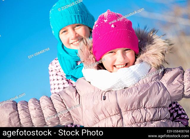 Two cute girls riding sled and having fun