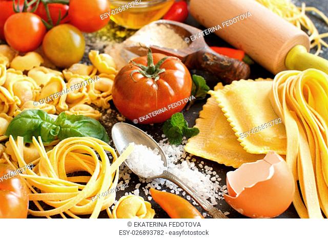 Fresh pasta and ingredients on a dark board close up