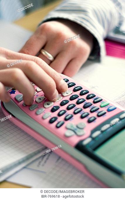 Schoolgirl doing homework, punching numbers into her calculator