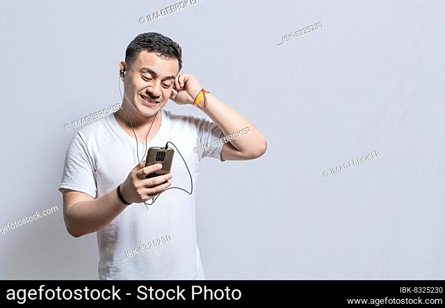Person listening to music with his cell phone with headphones isolated, Handsome man enjoying music with headphones isolated